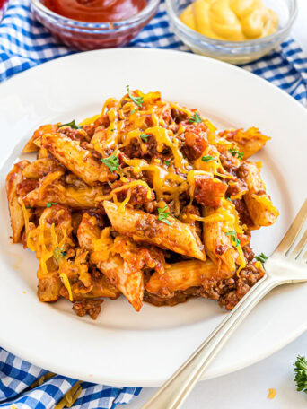 Close-up of pasta coated in cheesy sauce with bacon pieces and ground beef.