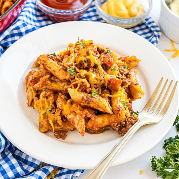 Close-up of pasta coated in cheesy sauce with bacon pieces and ground beef.