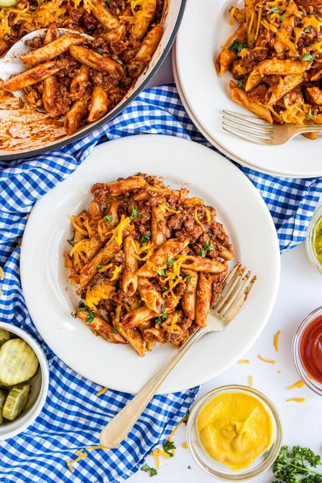 Overhead view of Bacon Cheeseburger Pasta Skillet with ketchup, mustard, and pickle relish on the side.