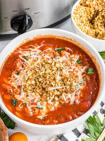 Bowl of Slow Cooker Chicken Parmesan Soup topped with toasted breadcrumbs and melted Parmesan cheese.