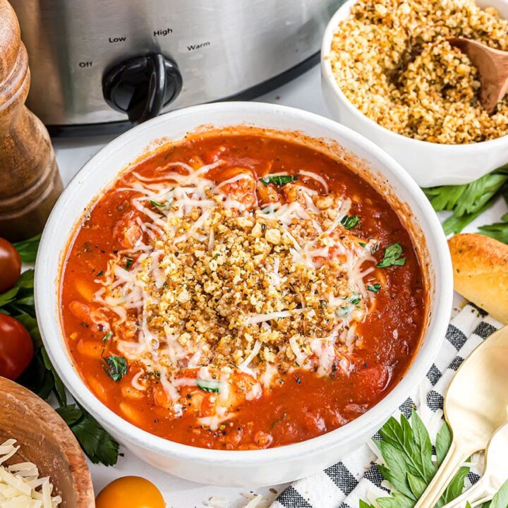 Bowl of Slow Cooker Chicken Parmesan Soup topped with toasted breadcrumbs and melted Parmesan cheese.