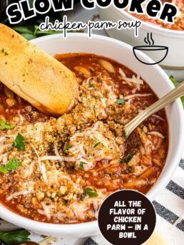 Bowl of Slow Cooker Chicken Parmesan Soup topped with toasted breadcrumbs and melted Parmesan cheese. Served with bread sticks