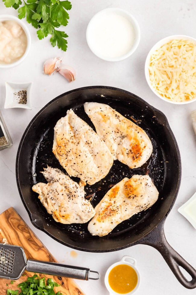 Chicken breasts searing in a skillet for one-skillet smothered chicken.