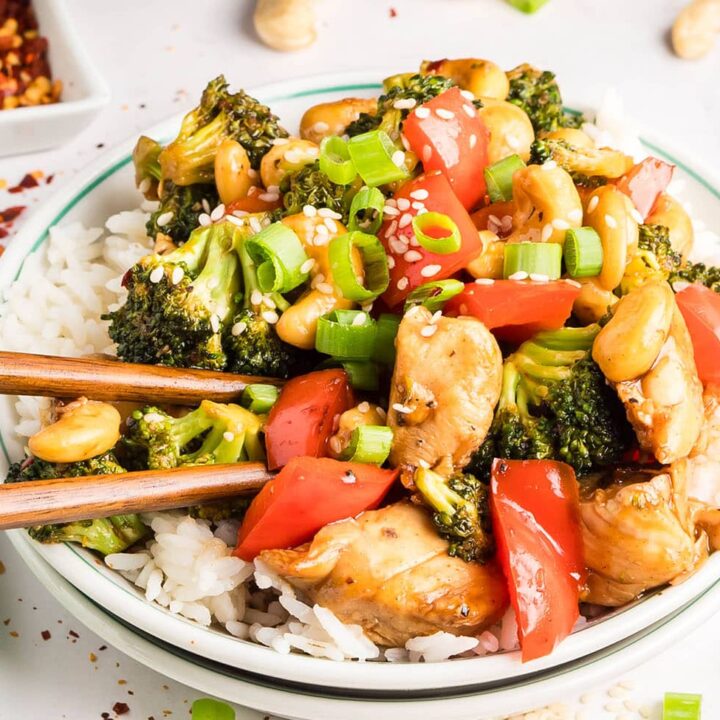 Cashew Chicken Stir Fry served over white rice with chopsticks — tender chicken, crisp vegetables, and cashews coated in a glossy, savory-sweet sauce.
