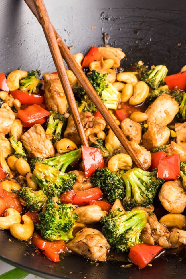 Close-up overhead shot of Cashew Chicken Stir Fry served with chopsticks — colorful veggies and cashews in a savory sauce.