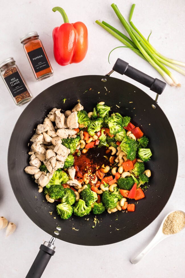 Cashew Chicken Stir Fry cooking in a wok with chicken, broccoli, red peppers, and cashews — step-by-step process from start to finish.