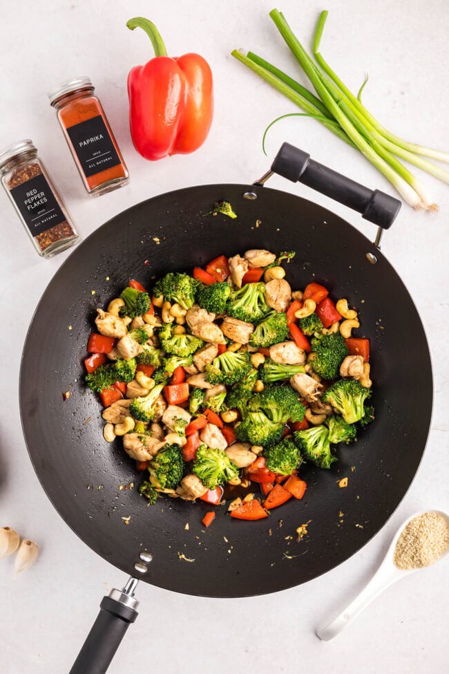 Cashew Chicken Stir Fry cooking in a wok with chicken, broccoli, red peppers, and cashews — step-by-step process from start to finish.