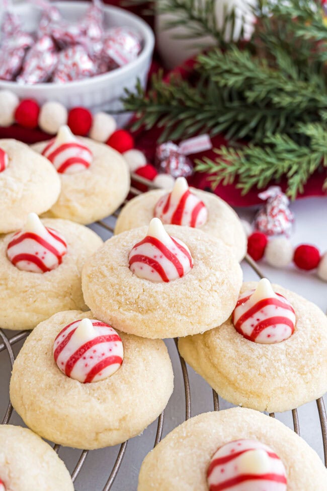 Candy Cane Kiss Cookies cooling on a wire rack, showing the melted peppermint Kisses in the center.