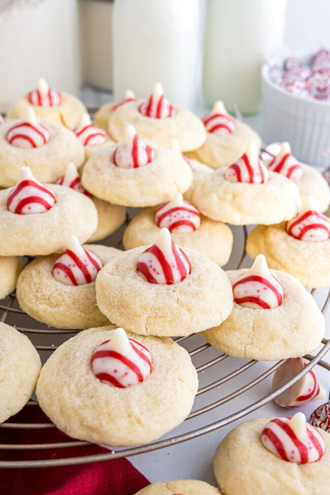 Candy Cane Kiss Cookies cooling on a wire rack, showing the peppermint Kisses in the center.