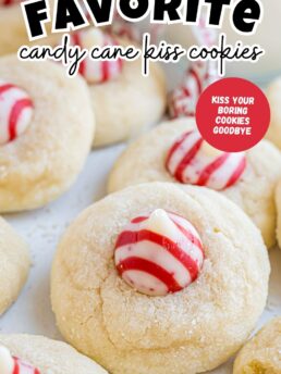 Overhead photo of Candy Cane Kiss Cookies stacked on a counter, showing sugar-coated cookies topped with striped peppermint Hershey’s Kisses.