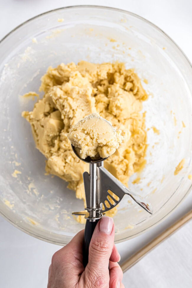 Close-up of cookie dough being scooped into balls for Candy Cane Kiss Cookies.