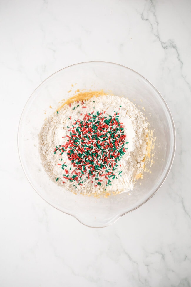 Blondie batter being mixed with flour and holiday sprinkles.