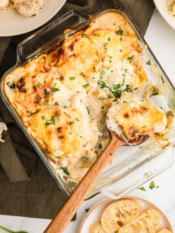 Unbaked Chicken Tortellini Casserole in a square glass baking dish and topped with shredded cheese.