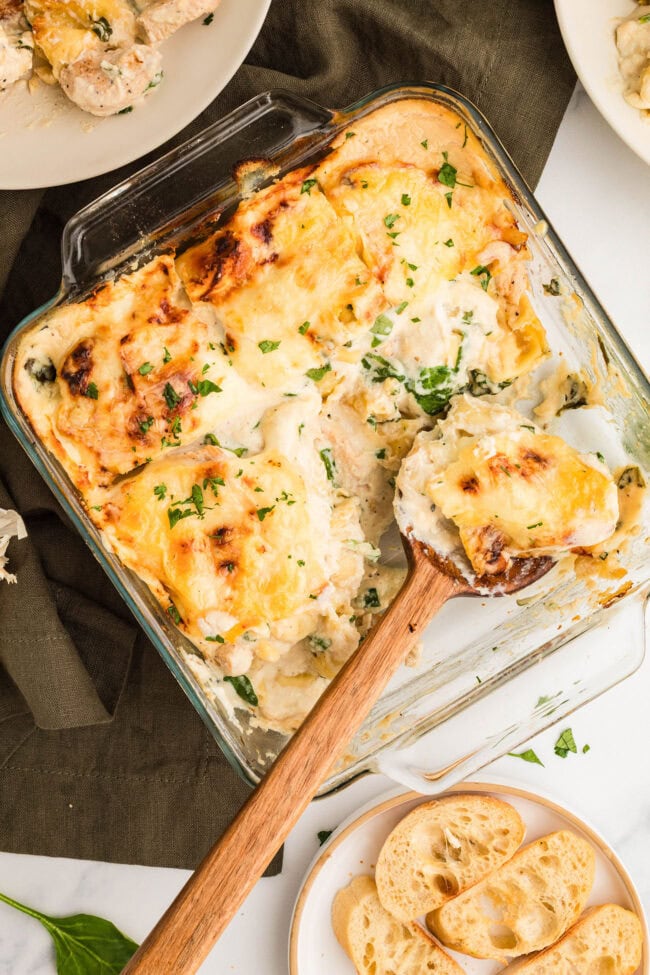 Chicken Tortellini Casserole in a glass baking dish with a serving scooped out using a wooden spoon.
