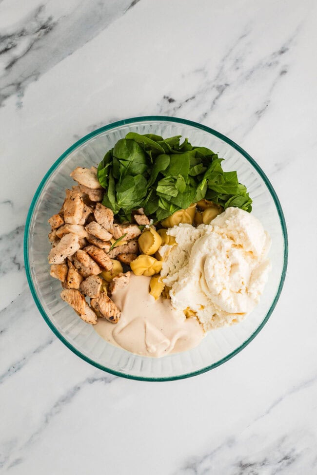 Chicken Tortellini Casserole ingredients to be mixed together in a glass dish before baking.