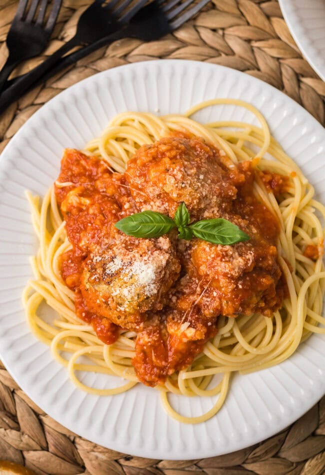 Chicken Parmesan meatballs served over spaghetti with marinara sauce, melted mozzarella, and fresh basil.