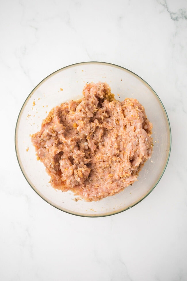 Ground chicken meatball mixture with breadcrumbs, Parmesan, and seasoning before shaping.