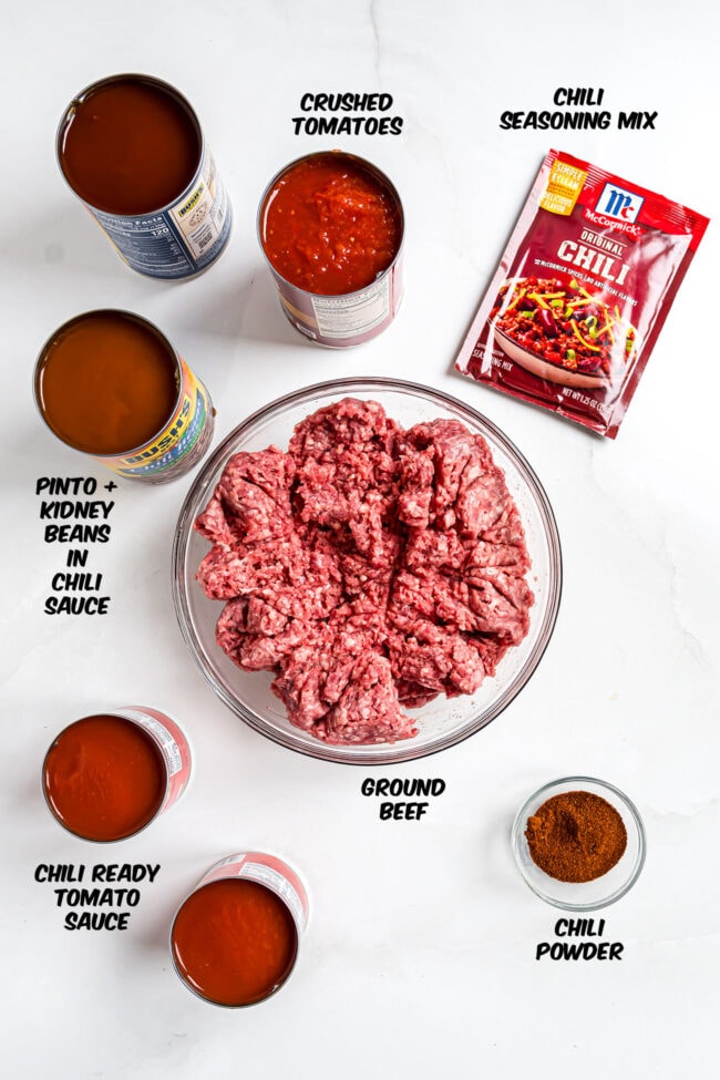 A bowl of raw ground beef, cans of beans, tomatoes and chili seasoning to make easy cowboy chili