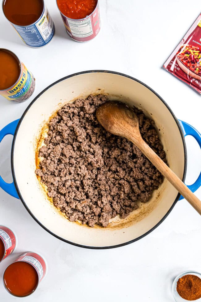 browning ground beef for chili in a blue dutch oven