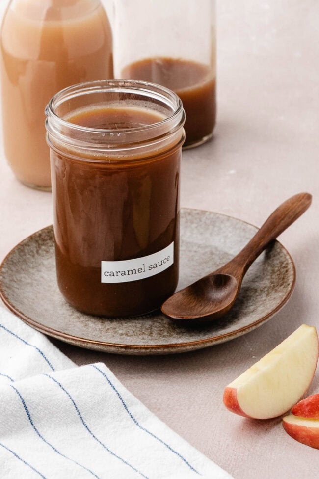 Jar of homemade salted apple cider caramel sauce with a wooden spoon.