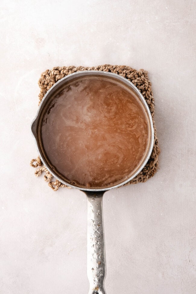 Apple cider simmering in a saucepan until reduced and concentrated.