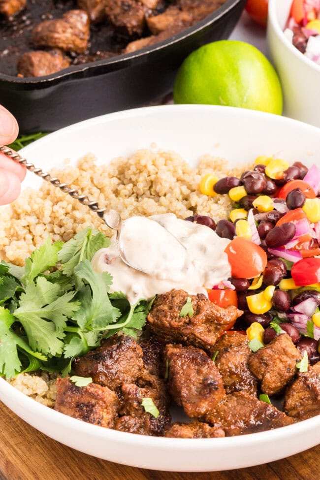 Close-up of a Southwest steak bowl with tender sirloin steak, rice, black bean and corn salad, and creamy Southwest sauce.