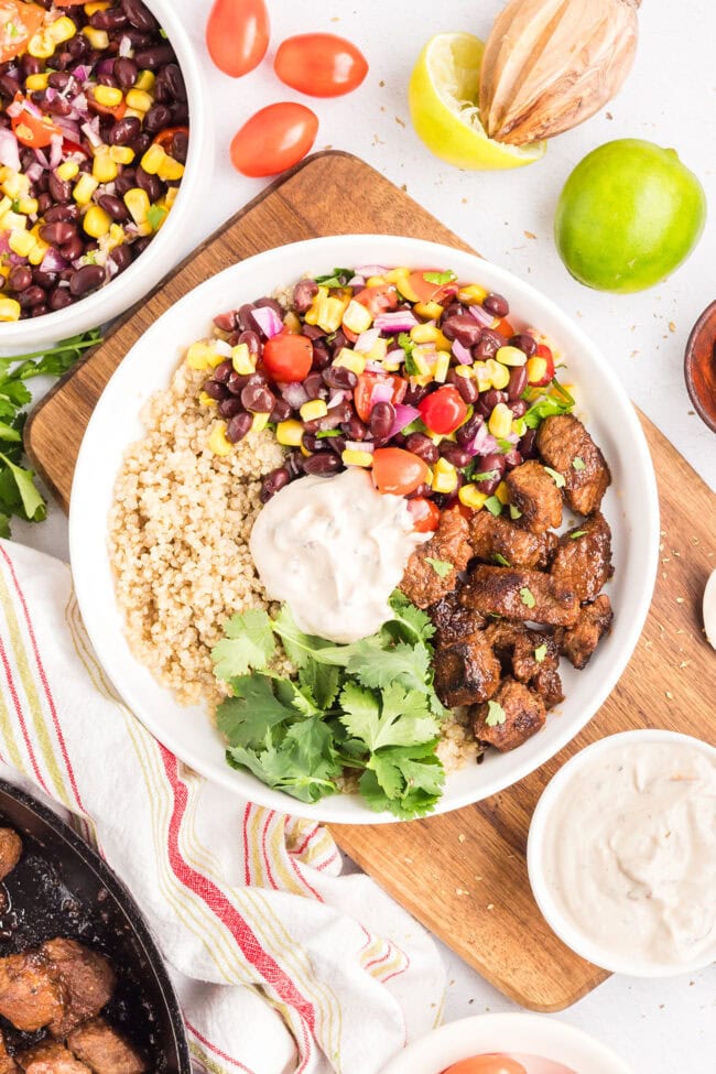 Finished Southwest steak bowl with seasoned sirloin steak, rice, black bean and corn salad, fresh cilantro, and creamy Southwest sauce.