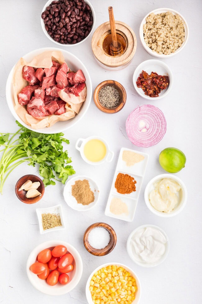 Ingredients for a Southwest Steak Bowl recipe including sirloin steak, rice, black beans, corn, tomatoes, red onion, cilantro, lime, sour cream, mayonnaise, chipotle peppers in adobo sauce, garlic, honey, avocado oil, and seasonings.