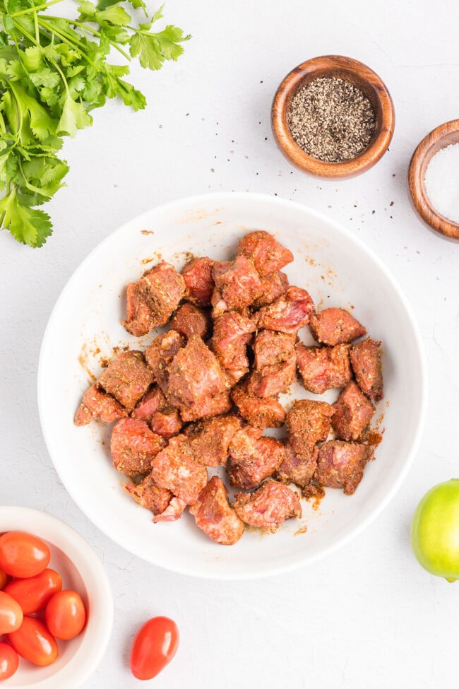 Marinating cubed sirloin steak with lime juice, avocado oil, and Southwest seasonings before cooking.