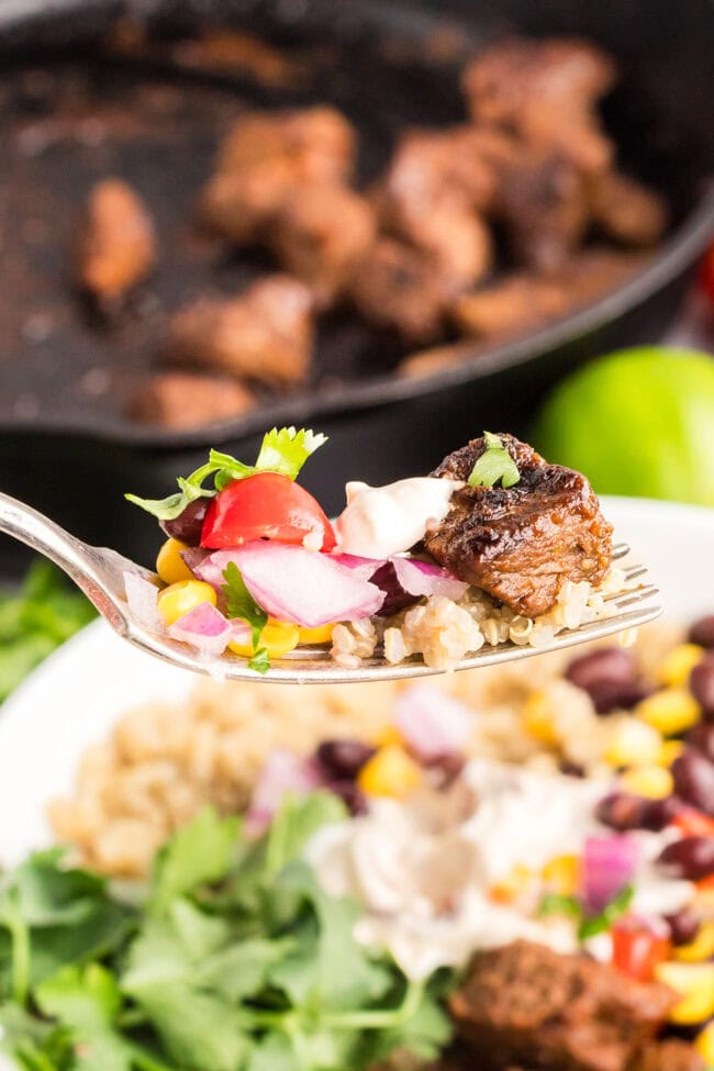 Spoonful of Southwest steak bowl with seasoned steak, rice, corn salad, and creamy Southwest sauce.