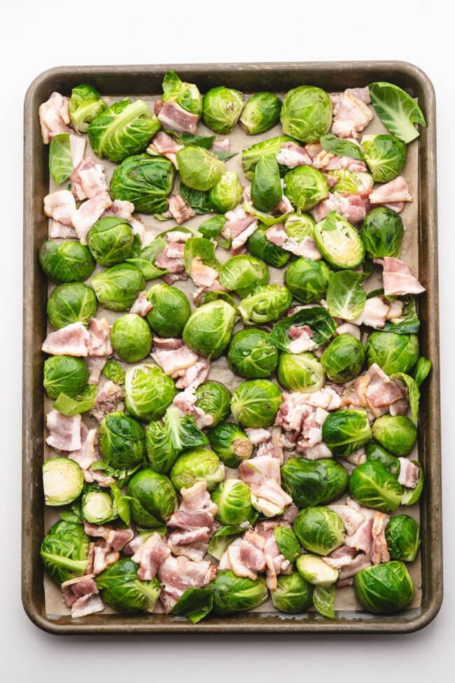 sprouts and chopped bacon arranged on a sheet pan