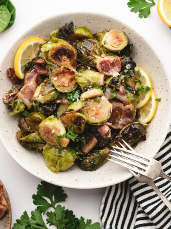 Maple bacon Brussels sprouts served on a plate with fresh lemon and parsley