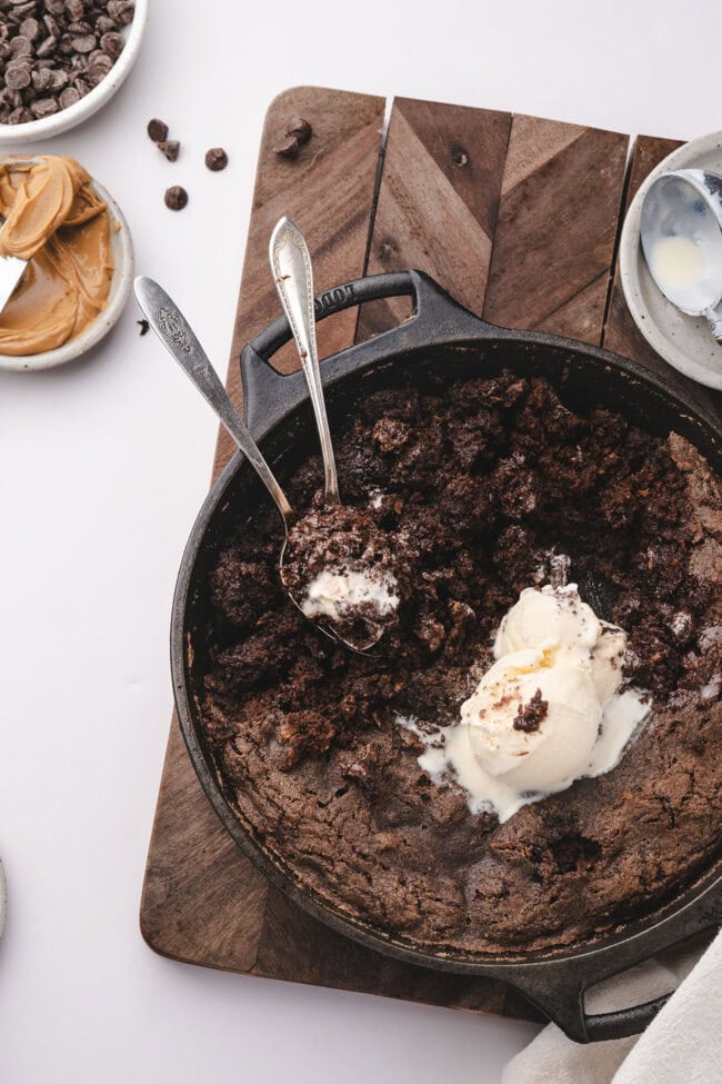 Chocolate cobbler in a skillet with vanilla ice cream and a spoonful lifted from the center