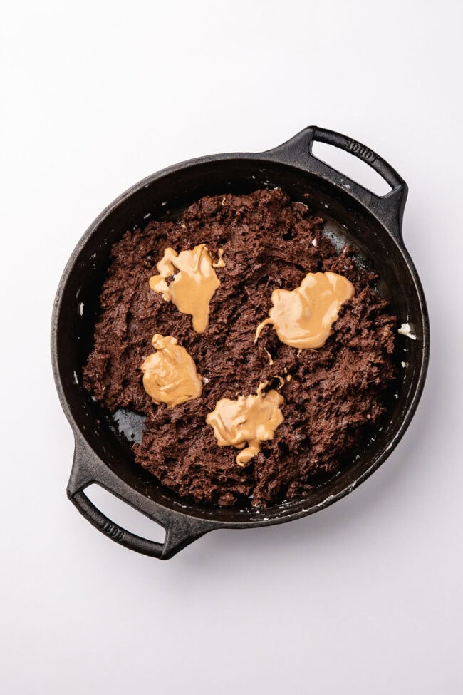 Dollops of peanut butter on chocolate cobbler batter in a skillet
