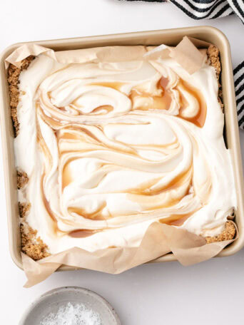 Salted caramel scoopable cheesecake with creamy filling and caramel swirls in a square baking dish