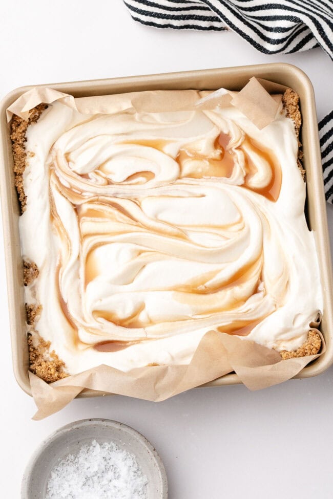 Salted caramel scoopable cheesecake with creamy filling and caramel swirls in a square baking dish