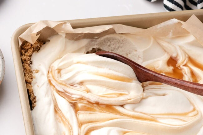Spoon scooping creamy salted caramel cheesecake from a graham cracker crust