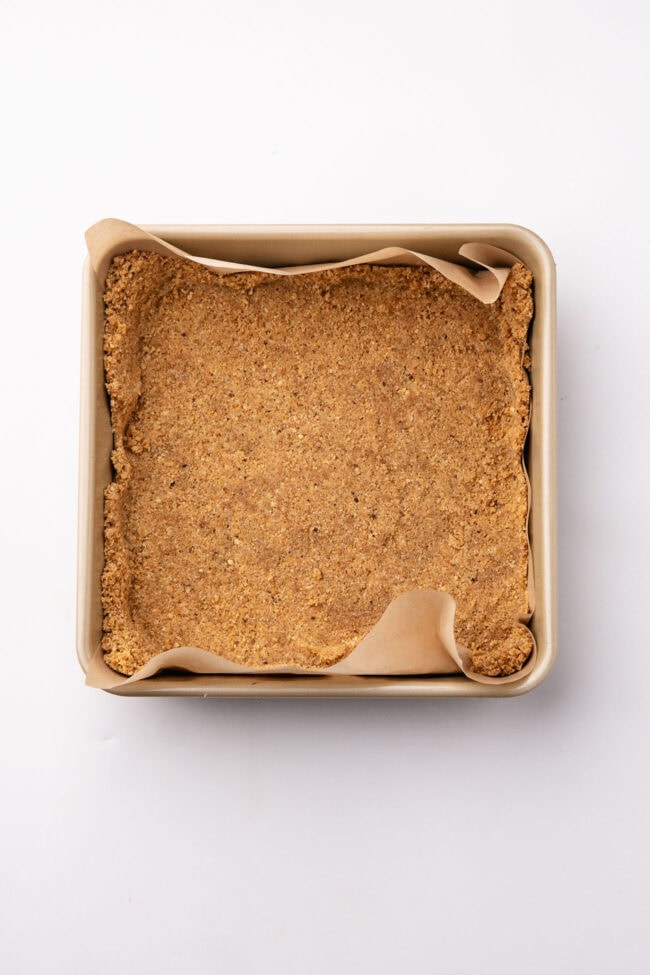 Graham cracker crust pressed into a parchment-lined square baking dish