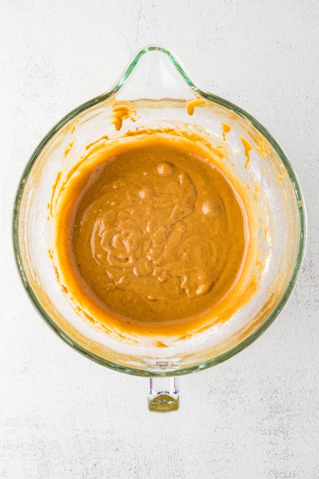 Mixed gingerbread muffin batter in a glass mixing bowl.