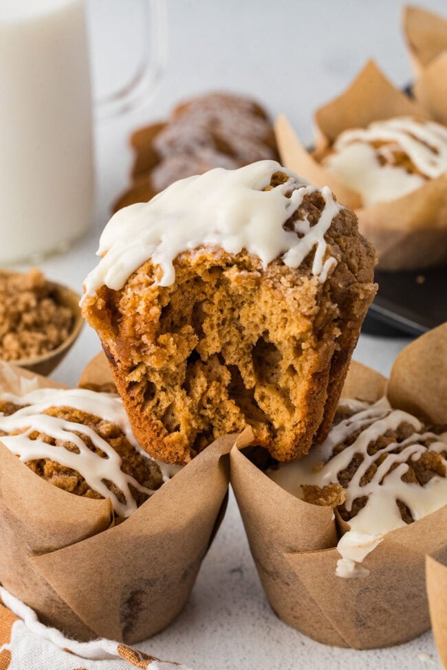 Gingerbread muffin broken open to show the inside beneath crumble topping and maple cream cheese icing.