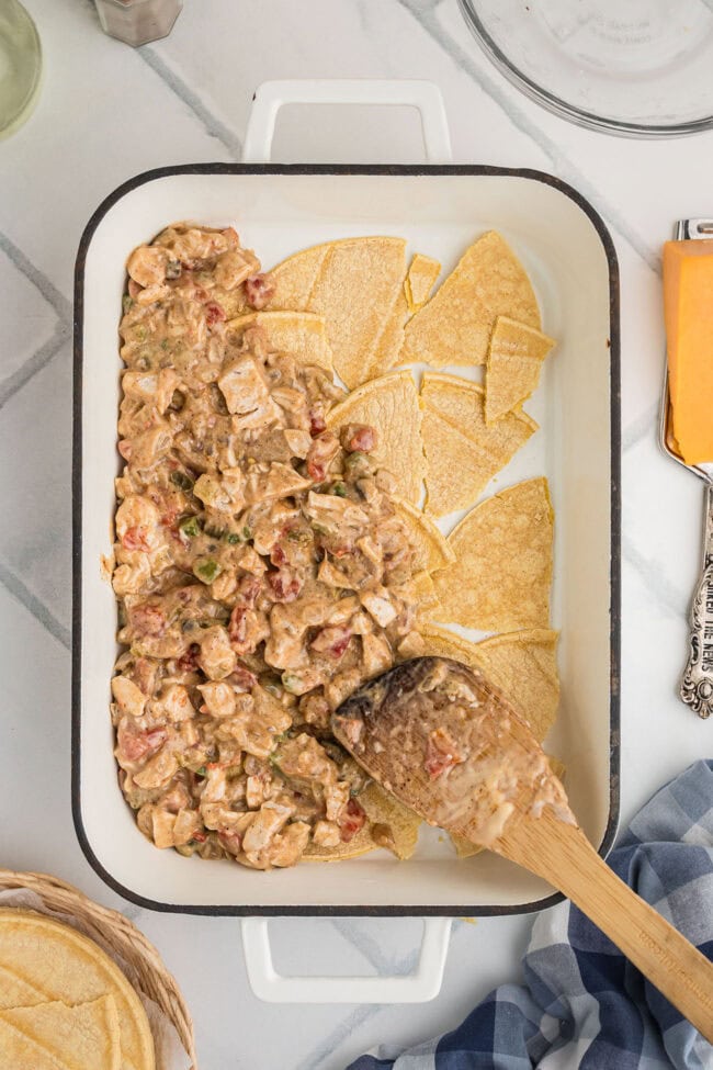 Creamy chicken filling spooned over a layer of corn tortillas.