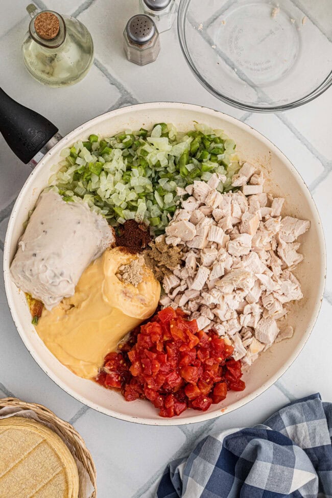 Cooked chicken, onion, bell pepper, canned soups, tomatoes, and seasonings in a skillet before mixing