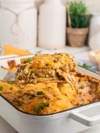 A spatula lifting a serving of King Ranch chicken casserole, showing the creamy chicken and tortilla layers.