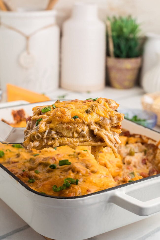 A spatula lifting a serving of King Ranch chicken casserole, showing the creamy chicken and tortilla layers.